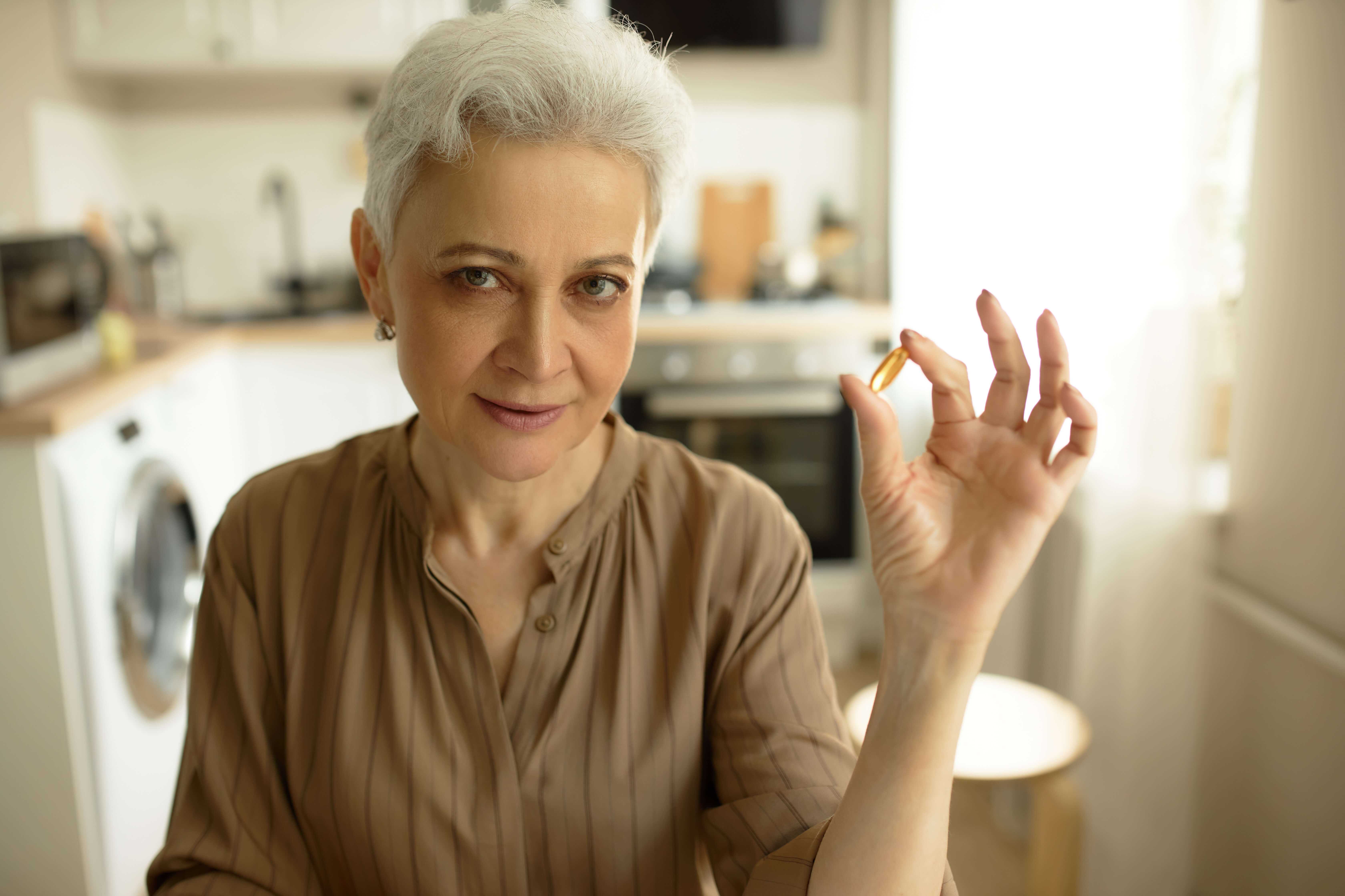 staršia žena s omega 3 kapsulou